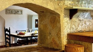 Un interior con un arco de piedra rústico que conduce a un comedor con una mesa preparada para dos.