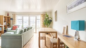 Un salón luminoso con un sofá, una mesa de madera y una estantería.