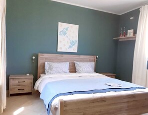 Ein Schlafzimmer mit einem hölzernen Bett, zwei Nachttischen, einem Wandregal mit Flaschen und einem gerahmten Bild.