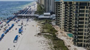 A beachside hotel with multiple floors, a pier, and a pool area.