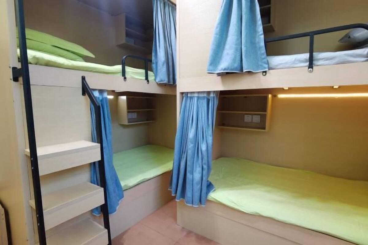 A bunk bed room with a shelf unit and curtains.
