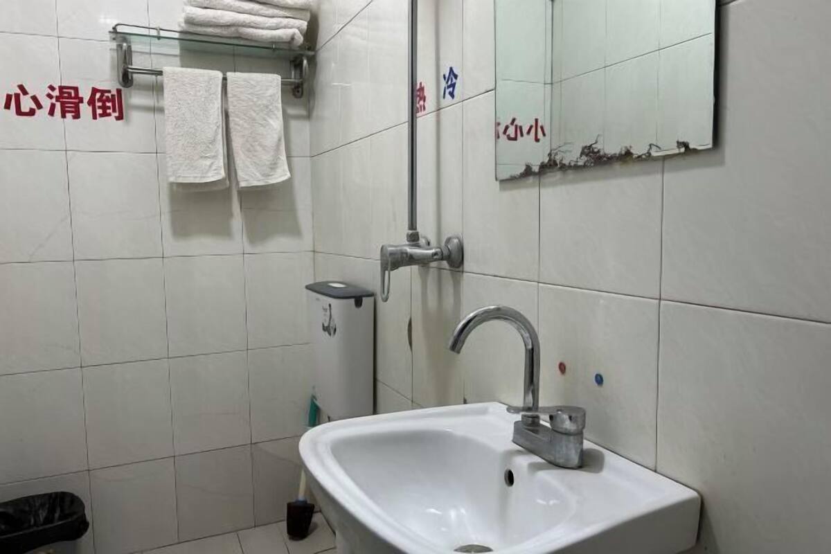 A bathroom with a white sink, a mirror, and a towel rack with towels.