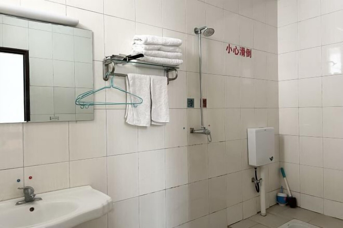 A bathroom with a sink, towel rack, shower, and a hand dryer.