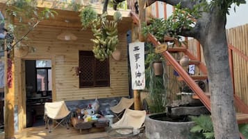 A wooden cabin with a balcony, a hanging plant, and a sign with Chinese characters.