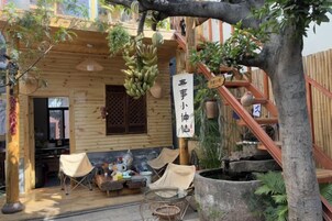 Uma cabana de madeira com varanda, uma planta pendurada e uma placa com caracteres chineses.