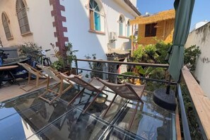 A glass-enclosed balcony with a wooden chair, a small table, and a potted plant. - Nilv Flower Time International Youth Hostel (Jianshui)
