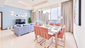 A modern living room with a sofa, dining table, chairs, and a TV. - Tiara - Luxury Palm Jumeirah (Dubai)