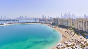 A coastal cityscape with a beach, high-rise buildings, and a marina. - Tiara - Luxury Palm Jumeirah (Dubai)
