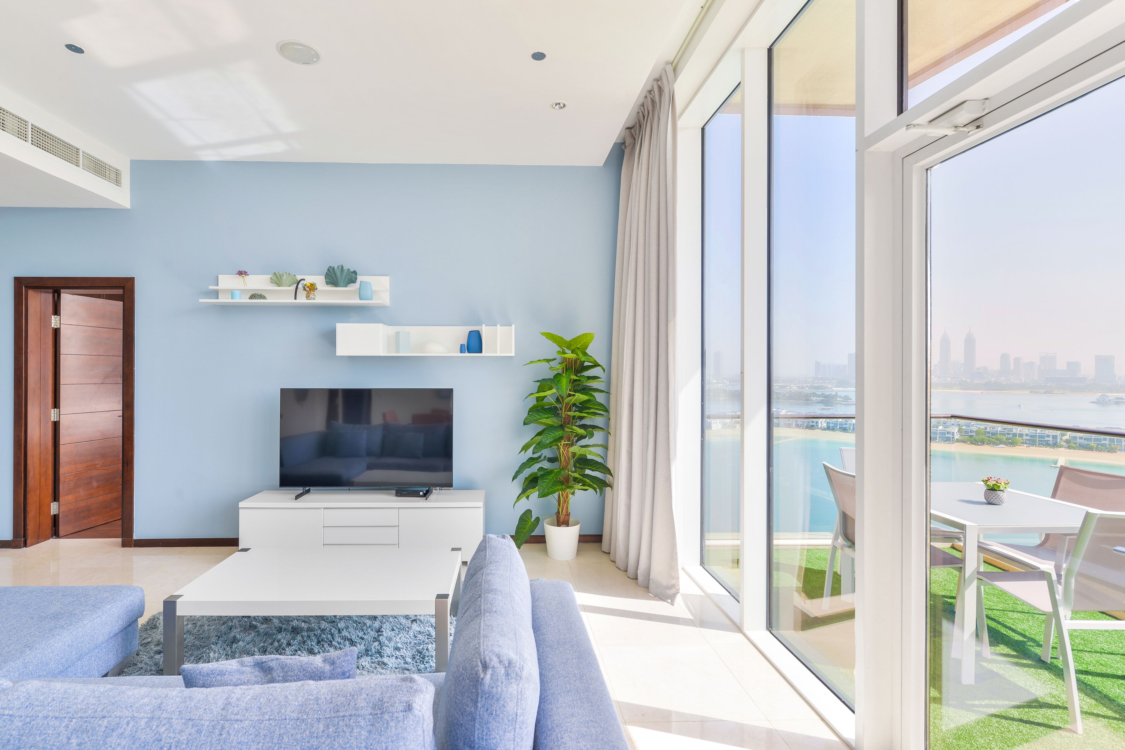 A modern living room with a TV, sofa, and potted plant.