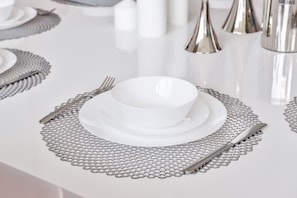 Een tafel gedekt met witte borden, bestek en een decoratieve tafelmat.