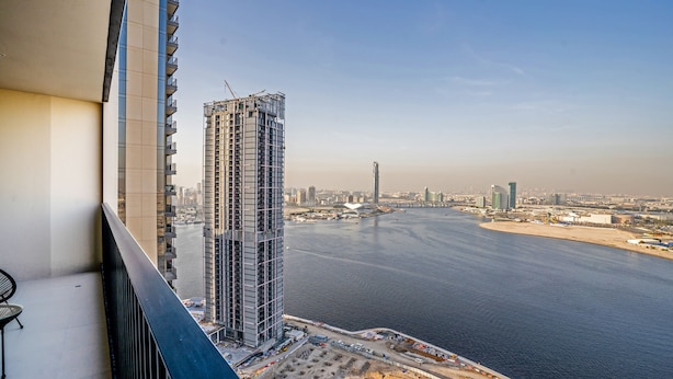 Un edificio alto con una grúa de construcción, vista al mar y cielo despejado.