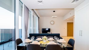 Un comedor moderno con una mesa de vidrio, sillas oscuras y un sofá azul al fondo.
