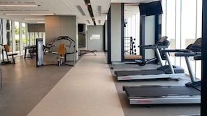 Un gimnasio moderno con cintas de correr, máquinas de pesas y un amplio ventanal que proporciona luz natural.
