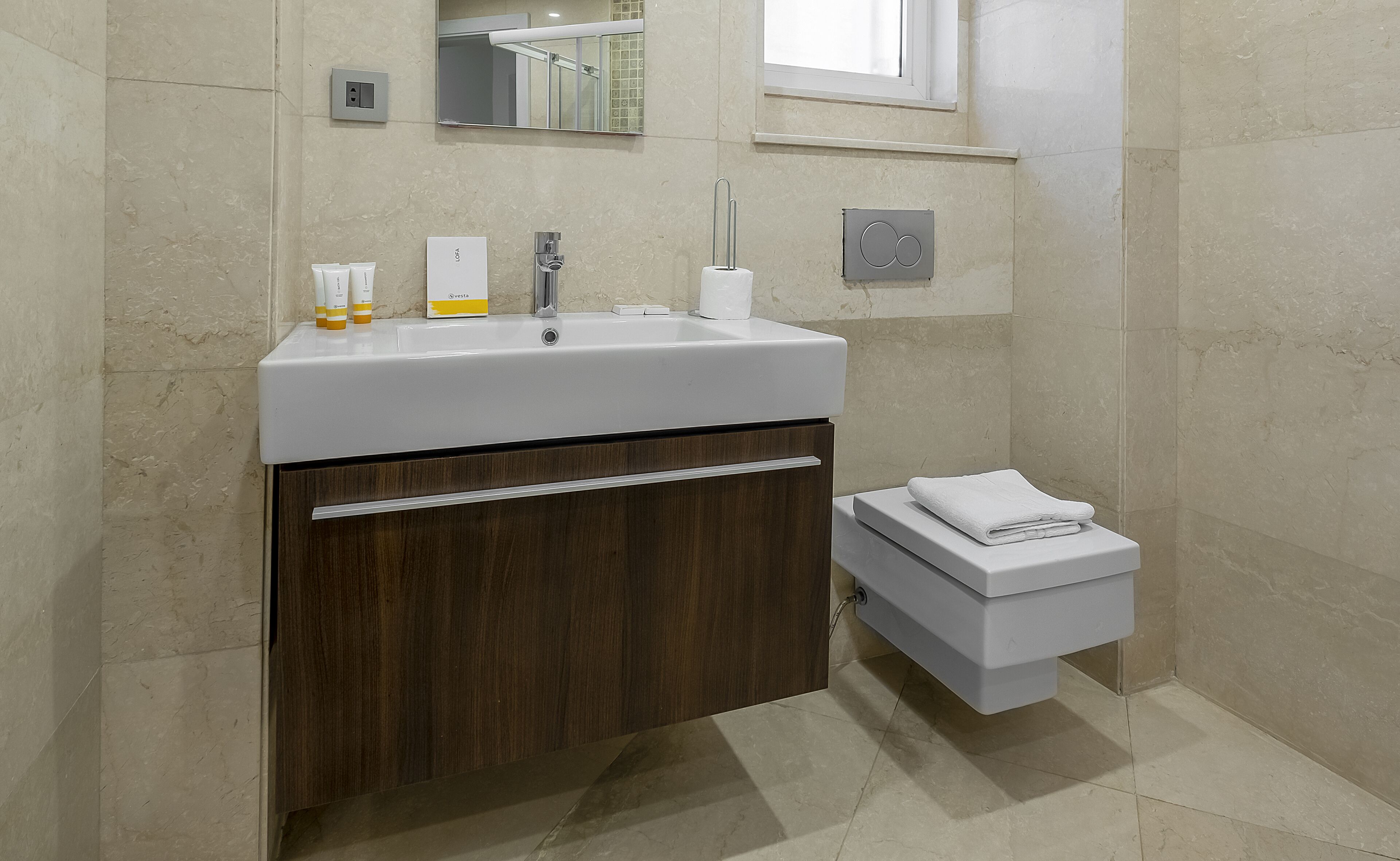 A bathroom with a white sink, wooden cabinet, and a white toilet.