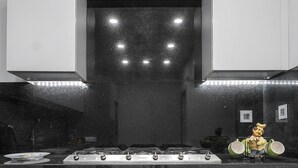 Cucina con piano cottura in acciaio inossidabile, forno integrato e schienale nero.