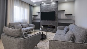Un soggiorno moderno con divani grigi, una televisione a schermo piatto ed scaffali a muro.