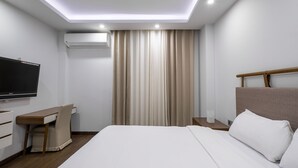Una camera d'albergo moderna con un letto, una scrivania, un televisore e un climatizzatore.