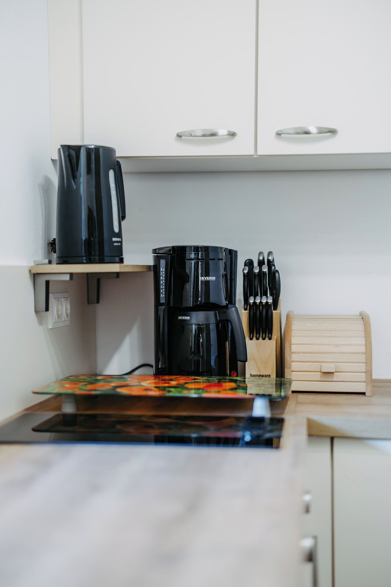 A kitchen with a coffee maker, knife block, and wooden storage box.