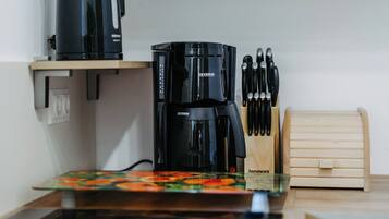 A kitchen with a coffee maker, knife block, and wooden storage box.