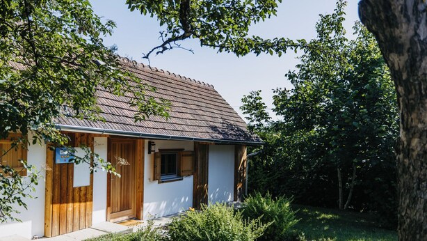 A single-story house with a sloped roof, a wooden door, and a small window. - Dahuam am Weinberg - Inner warmth (Winten)