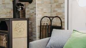 A modern living room with a grey sofa, a green pillow, a black heater, and a stone-patterned wall. - Dahuam am Weinberg - Inner warmth (Winten)