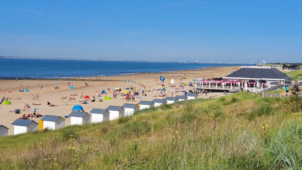 A beach with beach huts and a pavilion.