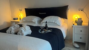 A neatly made bed with a dark headboard, a bedside table with a lamp, and a digital clock displaying 17:00.