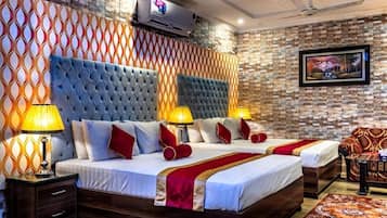 Quarto de hotel com duas camas, uma televisão, um ventilador de teto e parede com padrão.