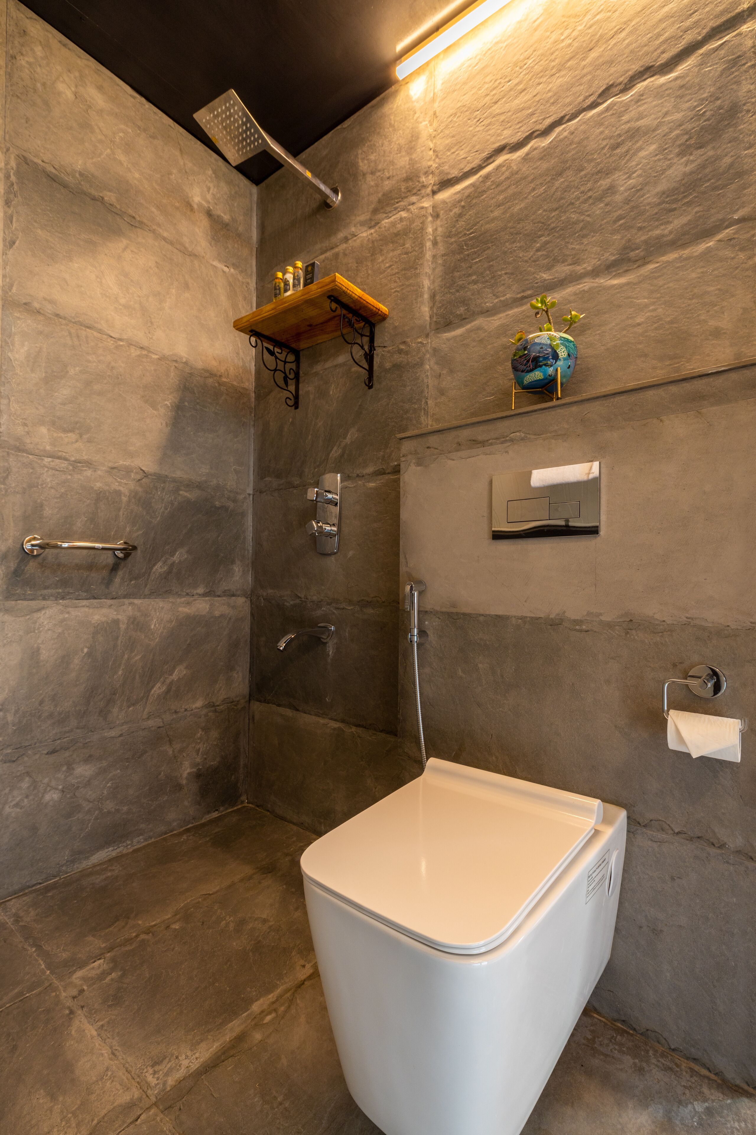 A modern bathroom with a shower, a toilet, and a shelf with toiletries.