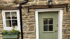 A stone building with a green door, a window with a white frame, and a black pipe. - Delightful 2 bed town house in historic Ludlow. (Ludlow)