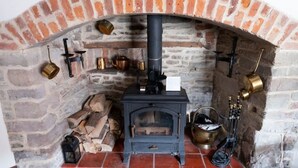 A traditional stone fireplace with a black wood stove, a brick arch, and various brass items on the wall. - Delightful 2 bed town house in historic Ludlow. (Ludlow)