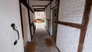 A narrow hallway with white brick walls and exposed wooden beams. - Delightful 2 bed town house in historic Ludlow. (Ludlow)