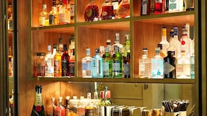 Una zona de bar con estantes llenos de botellas de licores, una botella de champán Moët & Chandon y una copa de martini sobre la barra.