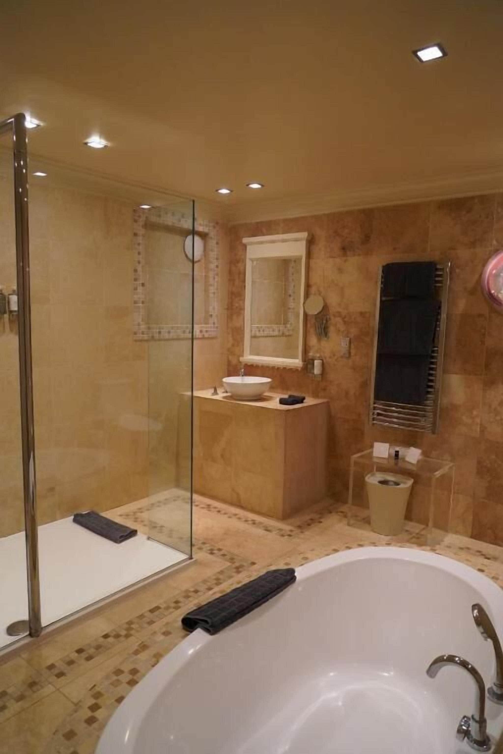 Un bagno moderno con doccia vetrata, una vasca da bagno indipendente e un mobile lavabo con specchio.