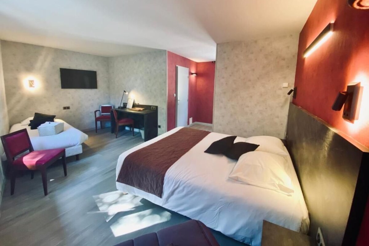 A hotel room with a large bed, a desk, and a chair.