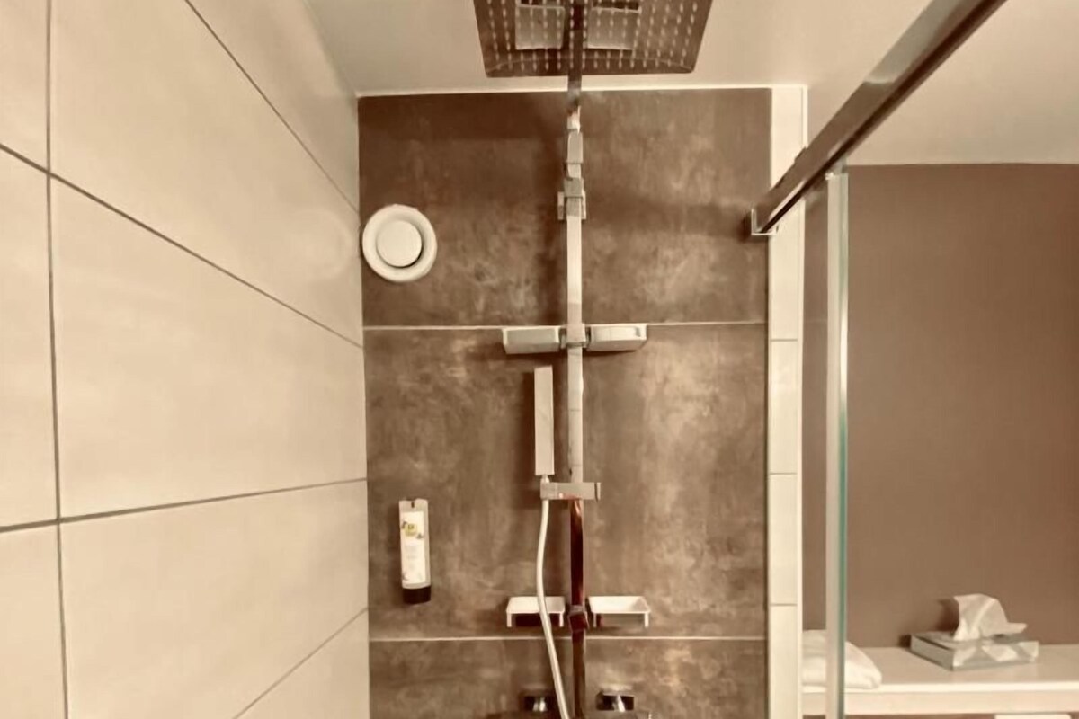 A modern bathroom with a shower, tiled walls, and a glass partition.