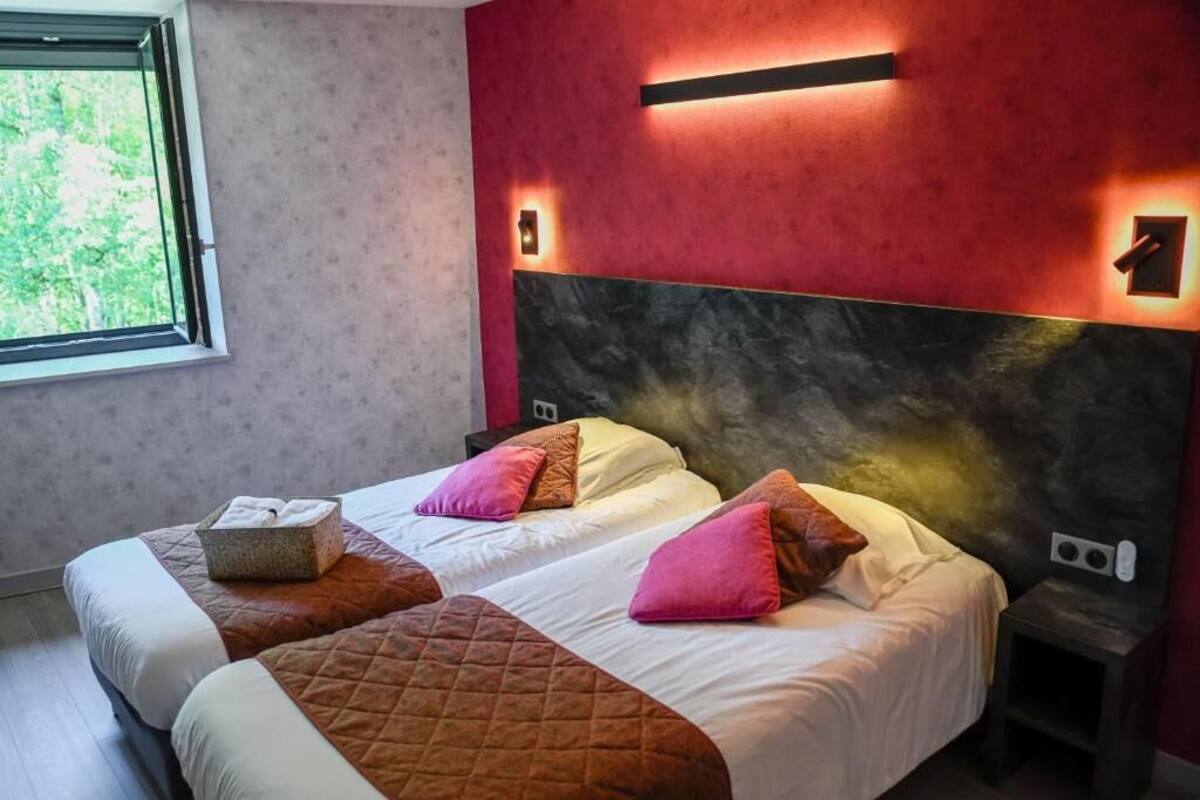 A hotel room with two beds, a large window, and a red accent wall.
