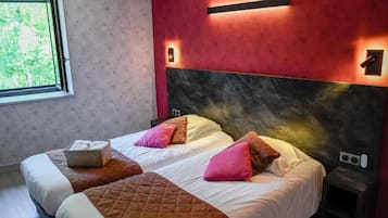 Habitación de hotel con dos camas, un ventanal grande y una pared roja decorativa.