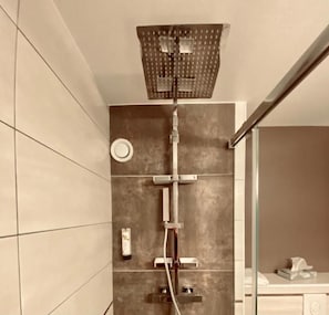 A modern bathroom with a shower, tiled walls, and a glass partition.
