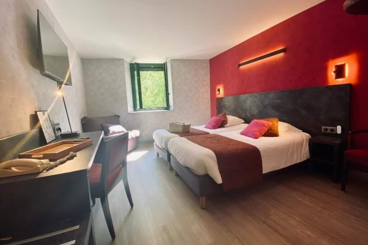 A modern bedroom with a large bed, a desk, and a window.