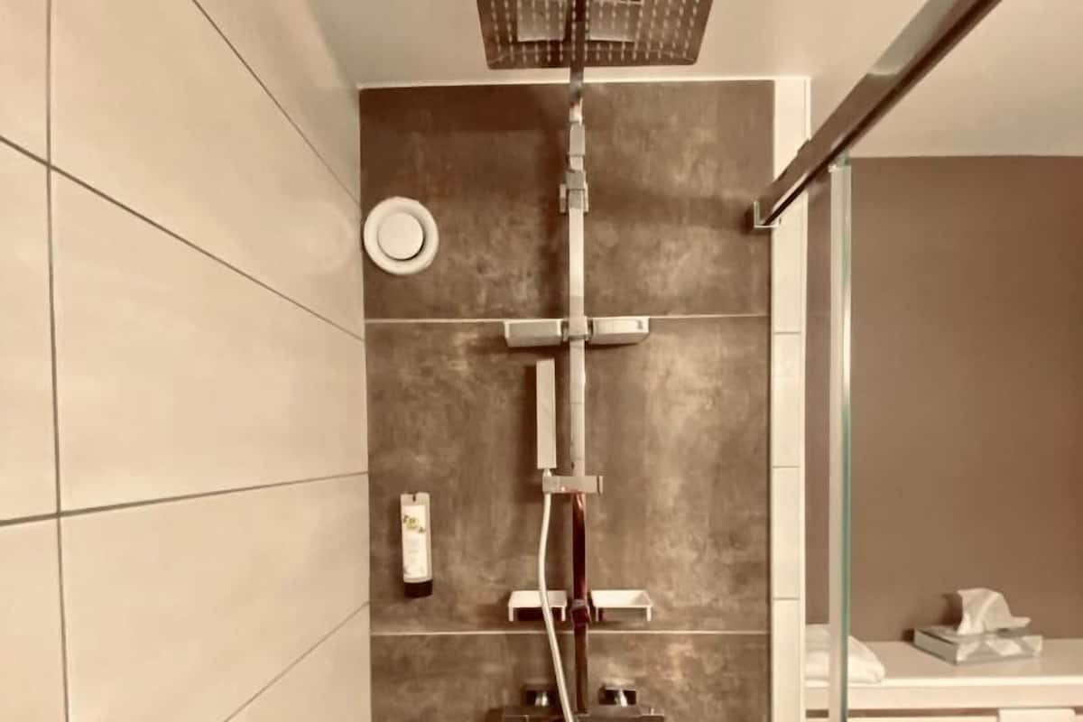 A modern bathroom with a shower, tiled walls, and a glass partition.