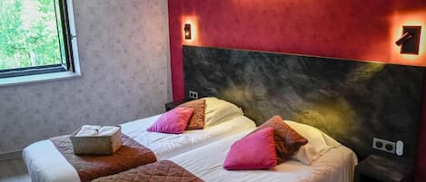 Una habitación de hotel con dos camas, un ventanal grande y una pared de acento roja.