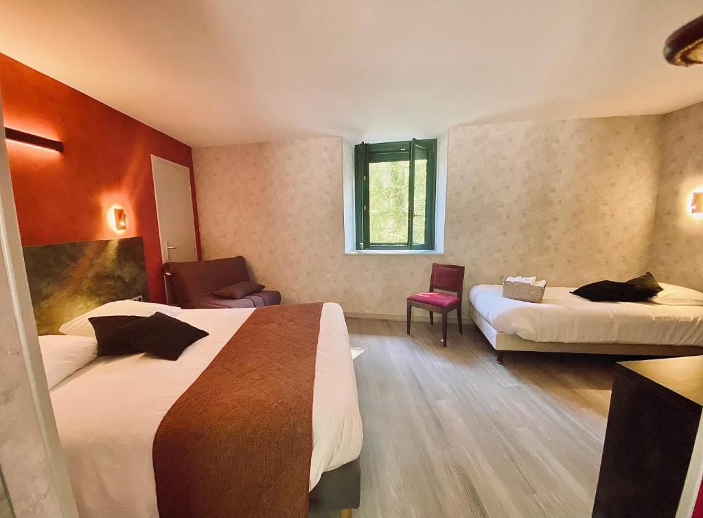 Ein Hotelzimmer mit zwei Betten, einem Sessel, einem kleinen Tisch und einem Fenster.