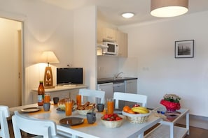 A dining area with a table set for breakfast, a television, and a kitchen in the background.