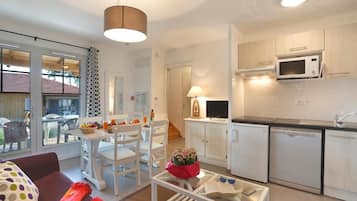 A compact living space with a kitchenette, dining area, and a glass door leading to an outdoor patio.