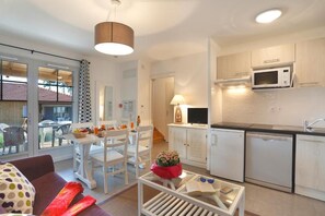 A compact living space with a kitchenette, dining area, and a glass door leading to an outdoor patio. - Logis Hotel Altitude et Spa (Pexonne)