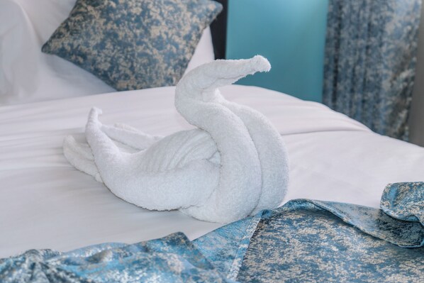 Un lit avec un drap blanc et une serviette en forme de cygne.