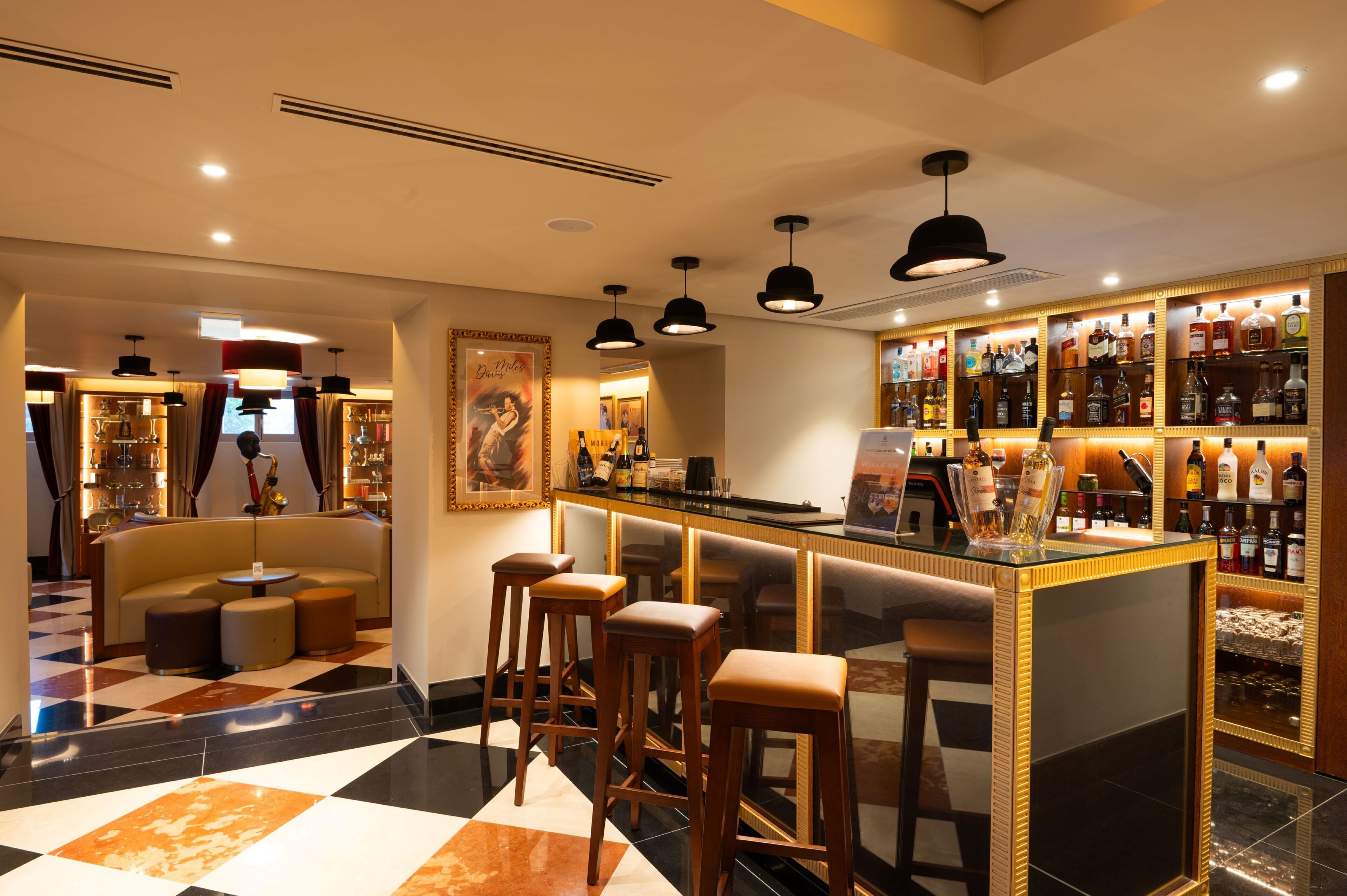 Una zona de bar con taburetes, una barra y una vitrina con licores.