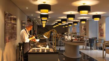 A modern restaurant with a central serving counter, overhead pendant lighting, and a clean, contemporary interior design.