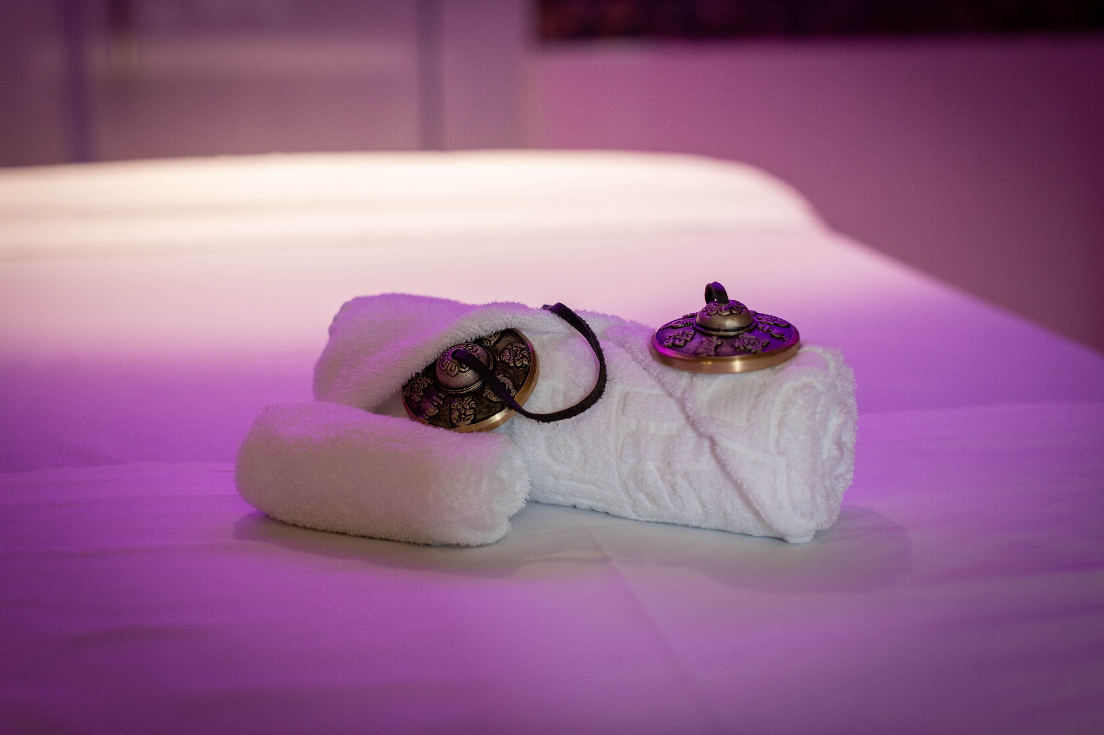 A bed with white linens and two decorative pillows with metallic tops.